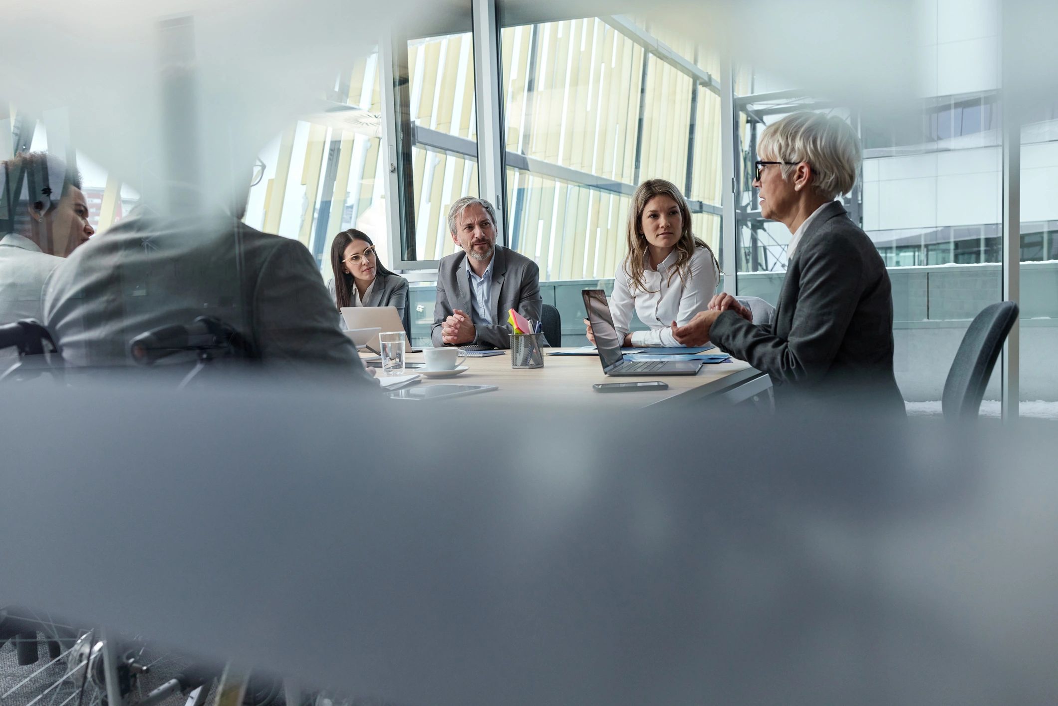 Senior businesswoman leading a meeting behind glass